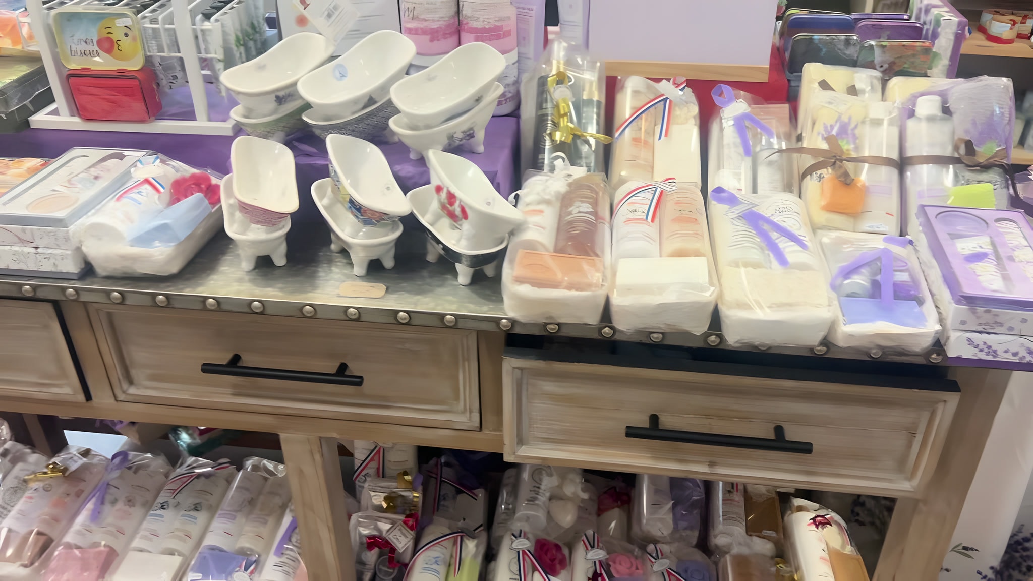 Petites baignoires en céramique et coffrets cadeaux rubannés sur un meuble en bois
