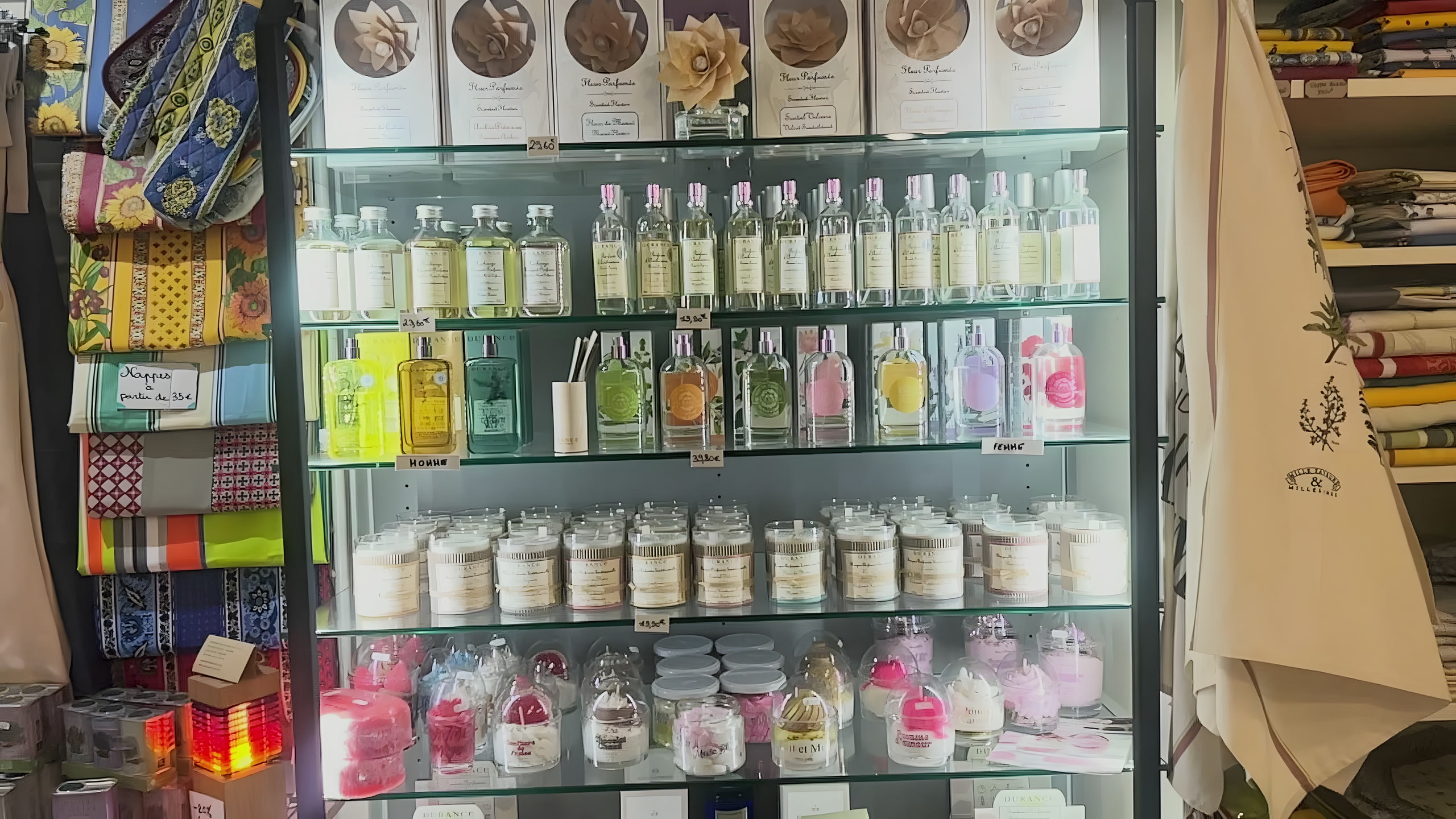 La vitrine de parfums, bougies et fleurs parfumées, entourée de tissus provençaux